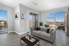 3-Bedroom Apartments in Mount Prospect, IL - 20 West - Living Room with Oversized Windows, a Private Balcony, and Grey Sofa with a Coffee Table
