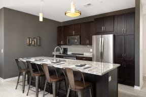 a kitchen with a marble counter top and stainless steel refrigerator
