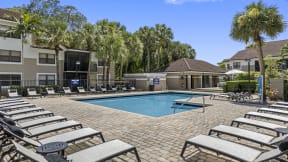 a swimming pool with chaise lounge chairs and palm trees in the background