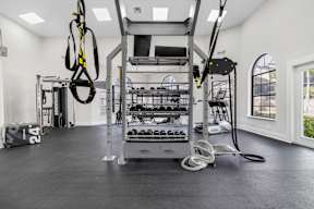 A gym with a weight rack, a rope, and a bag with the number 24 on it.