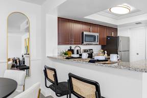 A kitchen with a black fridge and a black chair.
