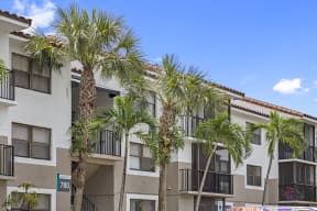 a picture of an apartment building with palm trees in front of it