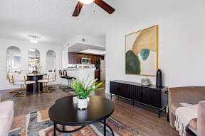 A living room with a black table and a painting on the wall.