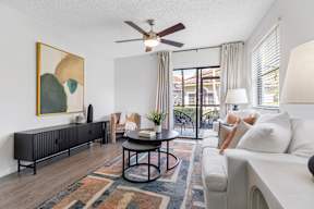 A living room with a ceiling fan, a painting, a sofa, a coffee table, and a rug.