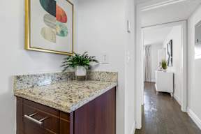 A kitchen with a marble countertop and a painting above it.