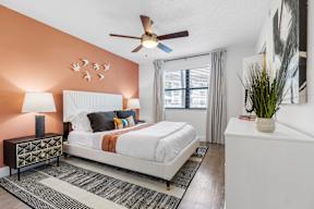 A bedroom with a white bed and a ceiling fan.