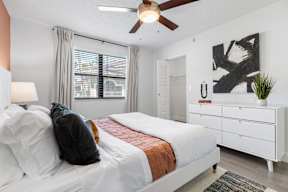 A bedroom with a bed, nightstand, and a ceiling fan.