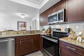 A kitchen with dark wood cabinets and stainless steel appliances.