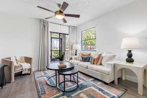 A living room with a white couch, a round table, and a ceiling fan.
