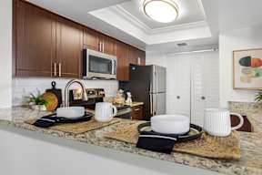 A kitchen with brown cabinets and a black refrigerator.