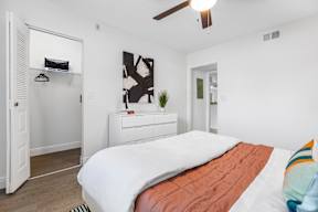 A bedroom with a bed, dresser, and a ceiling fan.