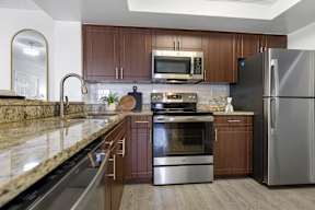 A modern kitchen with a granite countertop and stainless steel appliances.