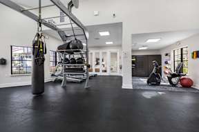 A gym with a punching bag, weights, and exercise equipment.