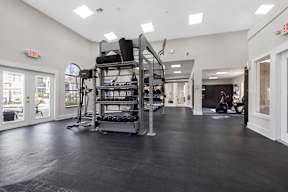 A gym with a weight rack and a person working out in the background.