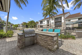 an outdoor kitchen with a grill and a table and chairs