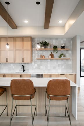 a kitchen with wooden cabinets and a white counter top with two chairs