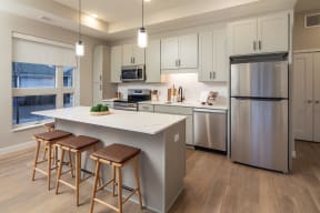 a kitchen with stainless steel appliances and a large island with three stools