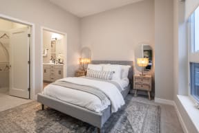a bedroom with a bed and two night stands and a door to a bathroom