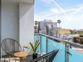 A balcony with a chair, table and plants with a view of a city.
