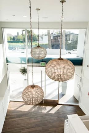 Three hanging light fixtures in a room with a view of the street outside.