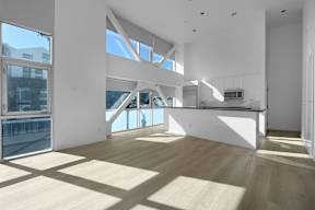 A spacious, well-lit room with wooden floors and large windows.