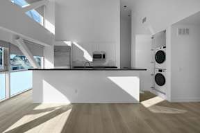 A modern kitchen with a large island and a washer and dryer in the laundry room.
