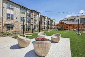 A sunny day at a residential complex with a patio area featuring wicker chairs and a table.