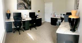 A room with a desk, chairs, and a computer.