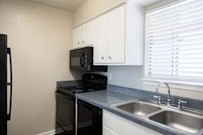 A black microwave is on top of a black stove in a kitchen.