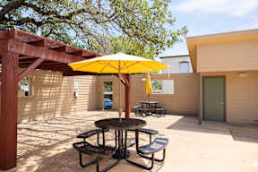 A yellow umbrella is on a table outside a building.