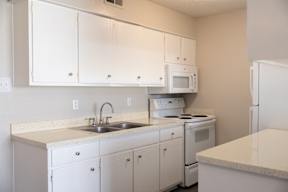 A kitchen with white cabinets and appliances.