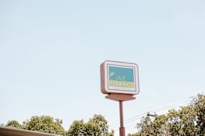A sign for Oak Terrace Community is shown against a clear sky.