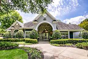A house with a stone archway entrance and a well-manicured lawn.