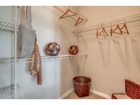 a walk in closet with a basket and hooks on the wall