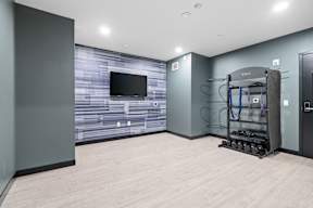 A yoga room with a wooden floor and a television on the wall.