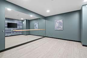 A yoga studio with a grey wall and a wooden floor.
