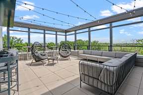 A rooftop terrace with a grey couch, two chairs and a table.