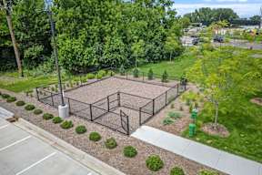 A pet playground with a fence and a green trash can.