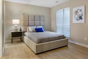 A bedroom with a large bed and a nightstand with a lamp.
