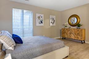 A bedroom with a bed, a dresser, and two framed pictures on the wall.