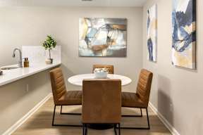 A dining room with a white table and brown chairs.