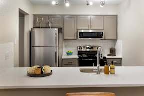 A kitchen with a white countertop and stainless steel appliances.