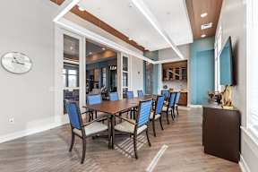 Shawnee, KS Apartments Near Kansas Speedway - Bonavia Luxury Apartments - Clubhouse Dining Room with Long Table, Chairs, Storage Cabinets, and Wall-Mounted TV.