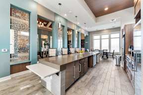 One Bedroom Luxury Apartments in Shawnee, KS - Bonavia Luxury Apartments - Clubhouse Kitchen with Stainless Steel Appliances, Expansive Island with Seating, and Pendant Lights.