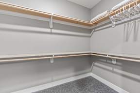 1 Bedroom Luxury Apartments in Shawnee, KS - Bonavia Luxury Apartments - Spacious Closet with Carpeting, Hanging Racks, and Generous Shelf Space.