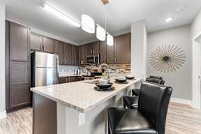 A modern kitchen with a large island and black chairs.