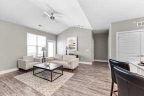 A living room with a ceiling fan and a rug on the floor.