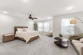 A bedroom with a large bed, a couch, and a ceiling fan.