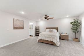 A bedroom with a large bed, a ceiling fan, and a painting on the wall.