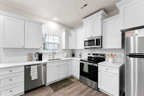 A white kitchen with a refrigerator on the right.